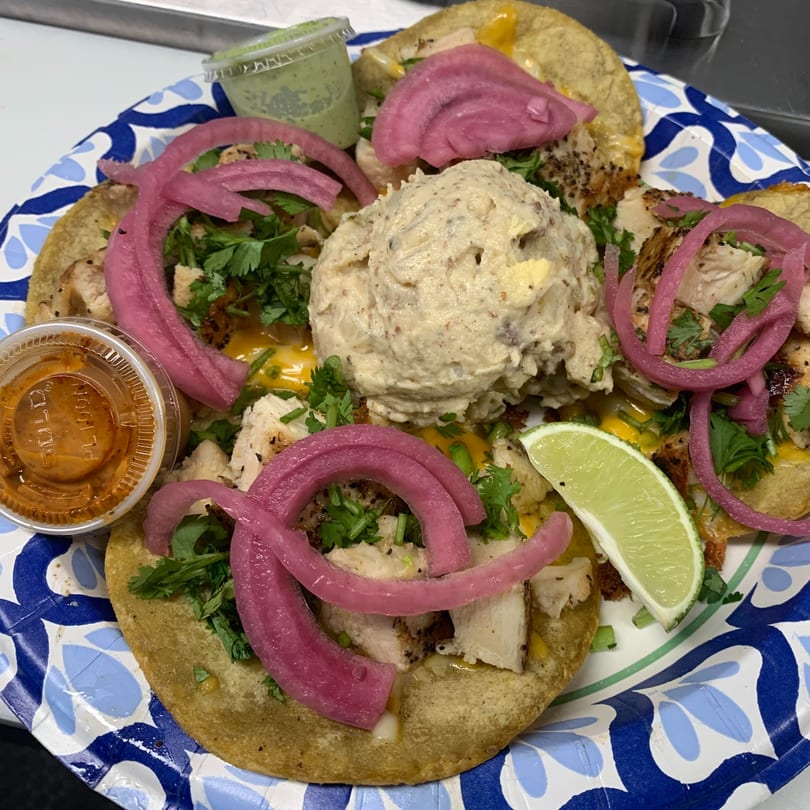 A plate of Street Food Kings tacos with chicken, pickled red onions, cilantro, and a side of lime.