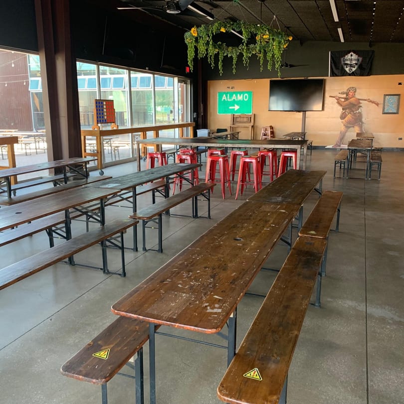 Empty Street Food Kings dining area with long wooden tables, benches, red stools, and an Alamo sign.