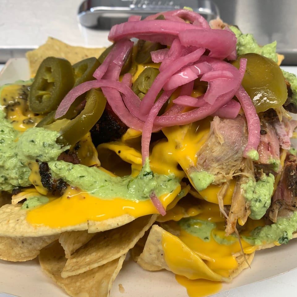 Mexican nachos with cheese, green sauce, pickled red onions, jalapeños, and meat.
