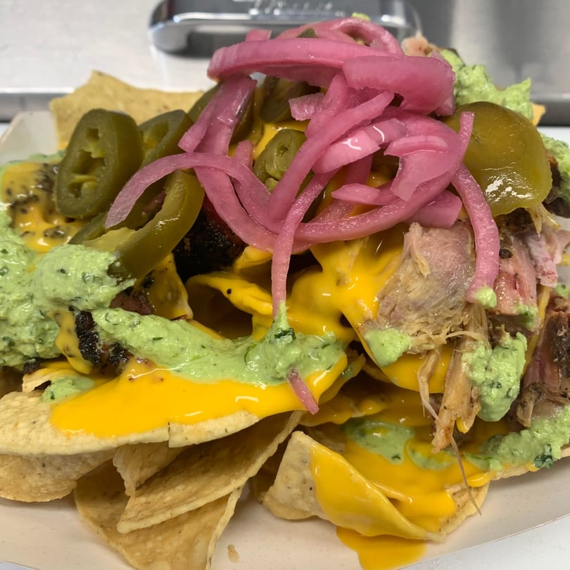 Mexican nachos with cheese, green sauce, pickled red onions, jalapeños, and meat.