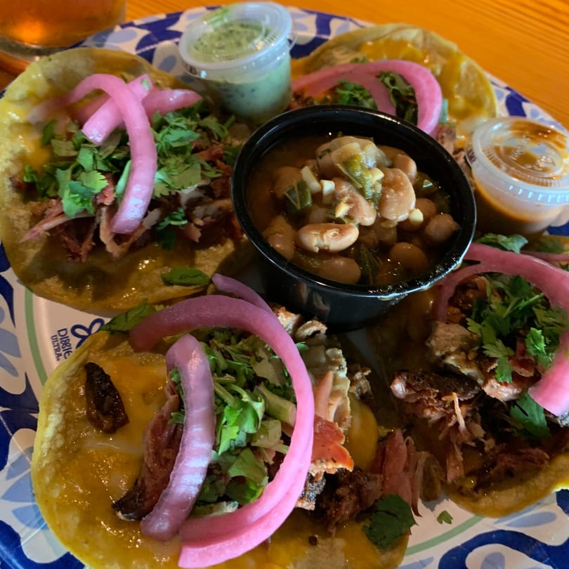 Street Food Kings' tacos with pickled onions, cilantro, and a side of beans and sauces.