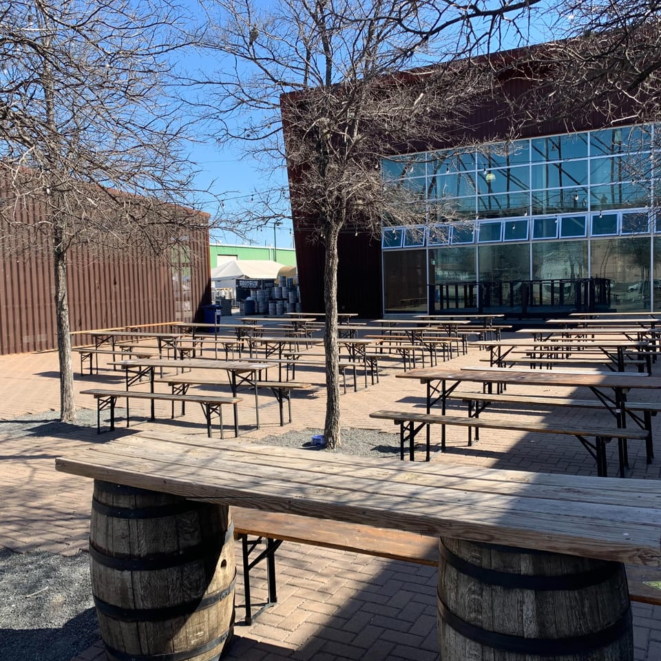 Outdoor patio with numerous picnic tables and benches, surrounded by buildings and bare trees.
