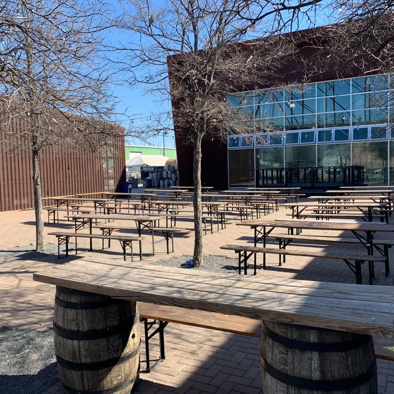 Outdoor patio with numerous picnic tables and benches, surrounded by buildings and bare trees.