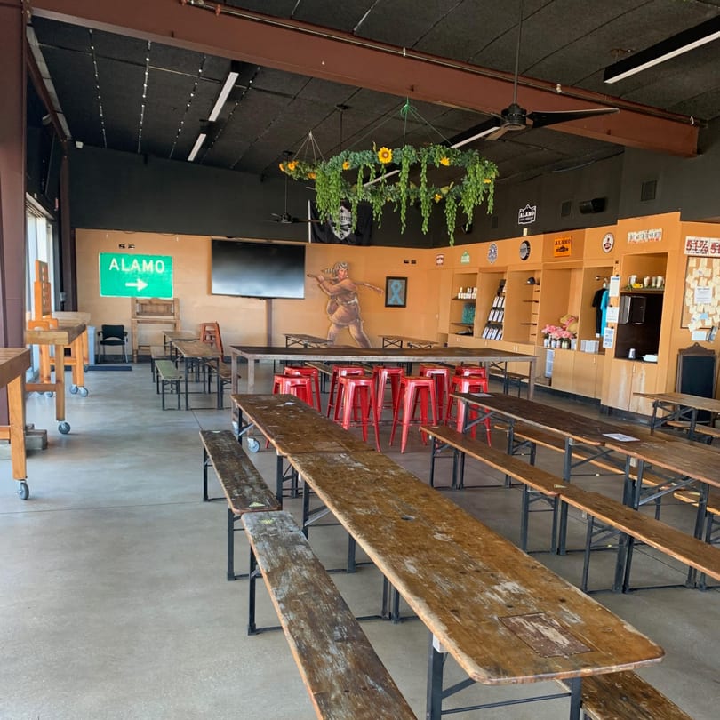 Spacious Street Food Kings dining area with long wooden tables, benches, red stools, and a mural.